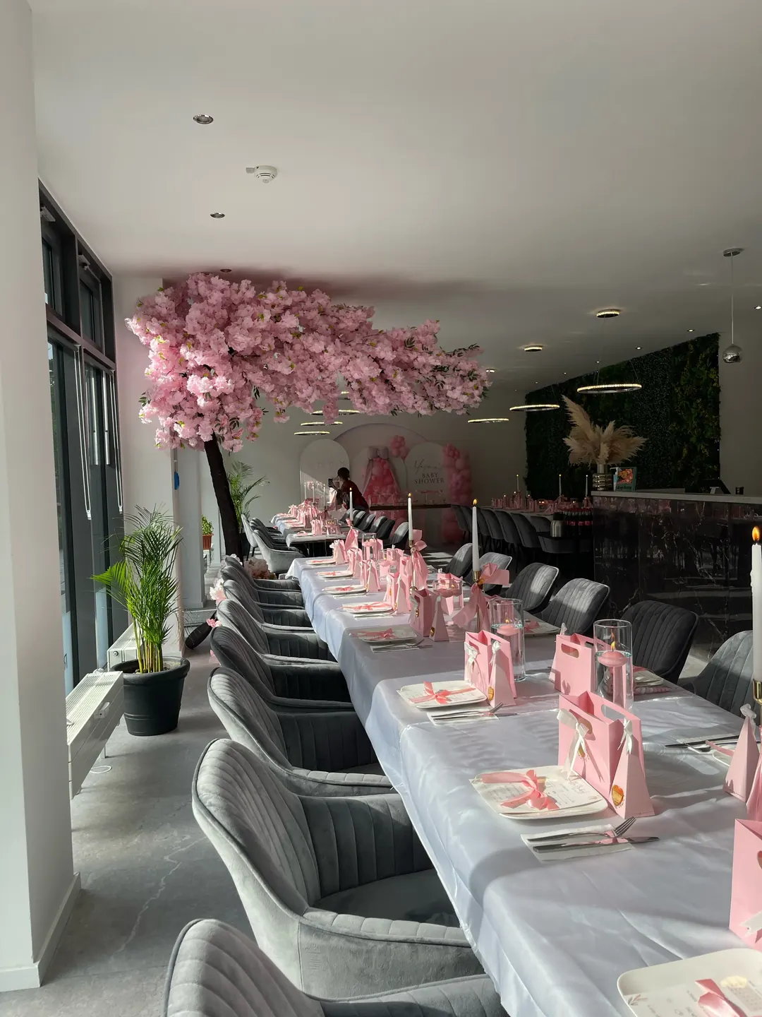 Lange festlich gedeckte Tafel in Rosa und Weiß unter dem Kirschblütenbaum